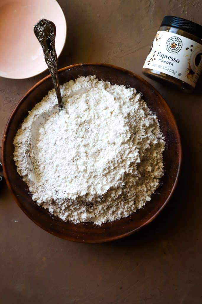 Dry flour mixture for cake in a wooden bowl with a for for mixing. 