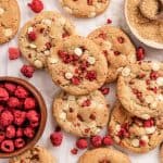 Square image of the raspberry white chocolate cheesecake cookies and bowl of raspberries.