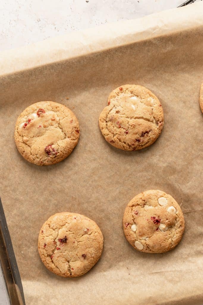 The baked cookies on a brown parchment lined cookie sheet. 