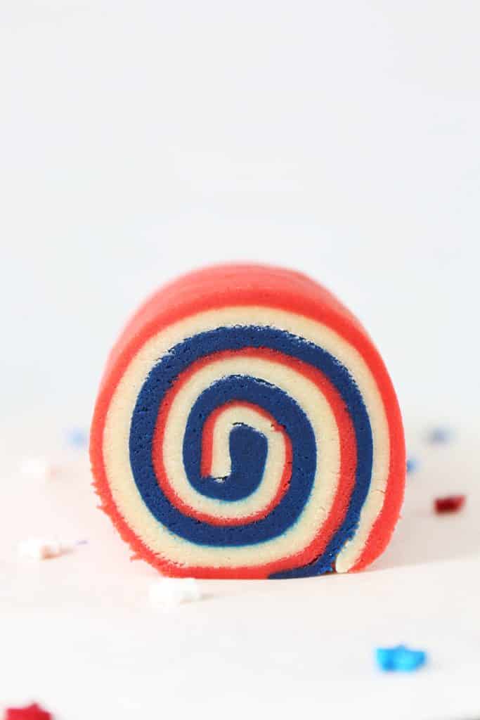 Up close photo of the edge of the red white and blue pinwheel log og cookie dough. 