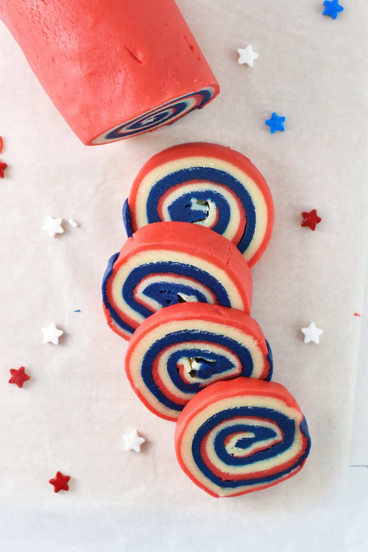 Cookie dough pinwheel log with a few cookies cut off and star sprinkles on the sides. 