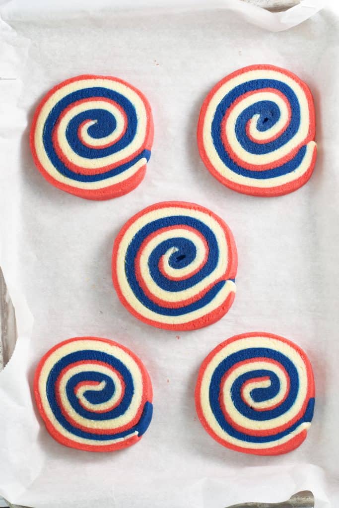 Slicing and placing the pinwheel cookies on a parchment lined cookie sheet. 