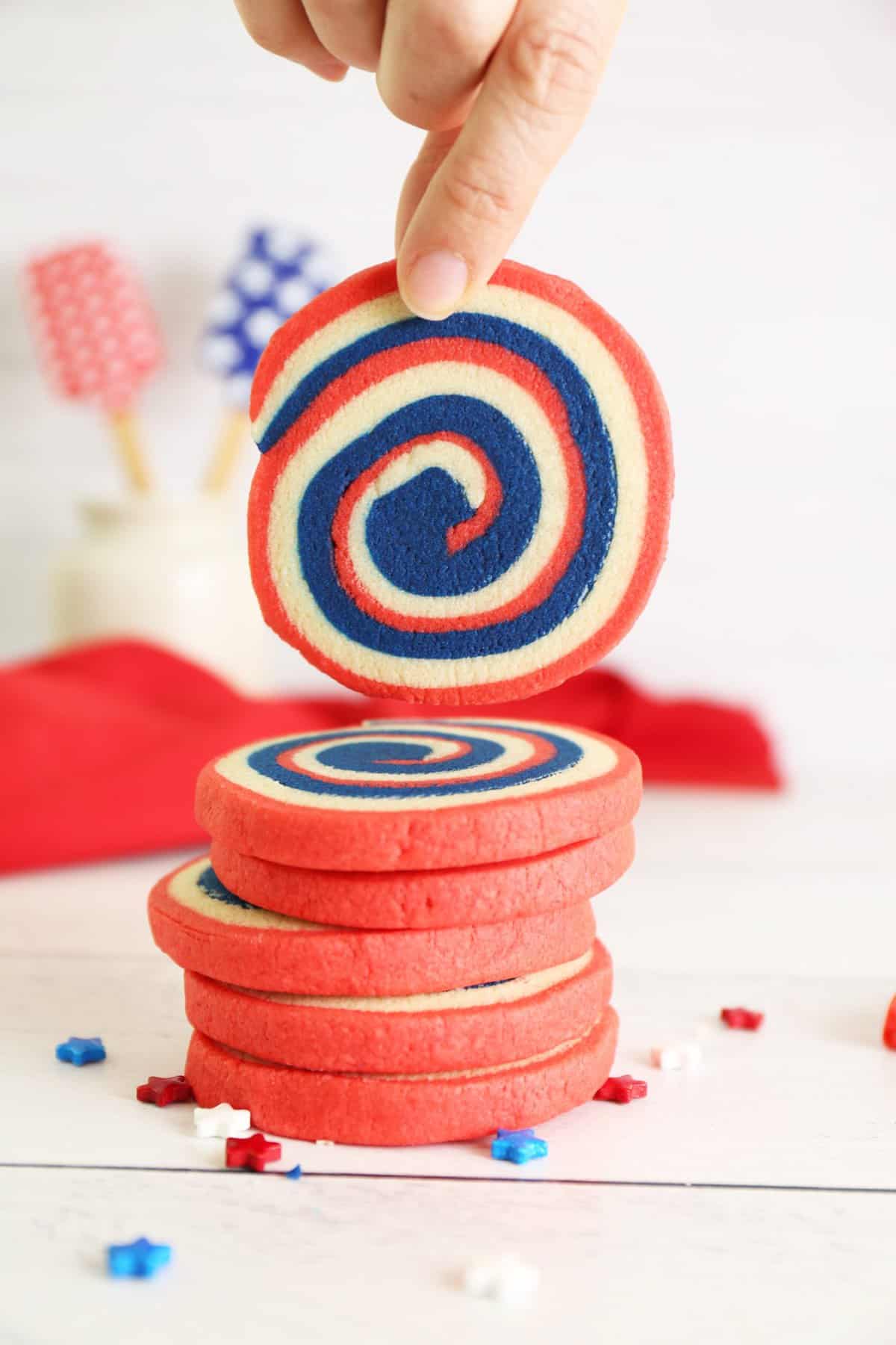 Hand pulling the pinwheel cookie off of the stack of cookies.