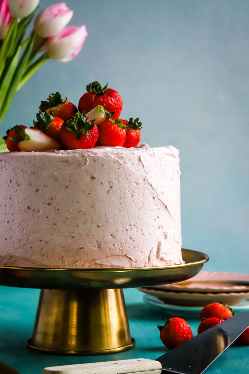 Cake with fresh strawberries on a gold metal stand. 