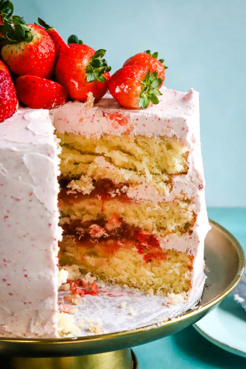 Cake with slices removed to show the vanilla and strawberry layers. 