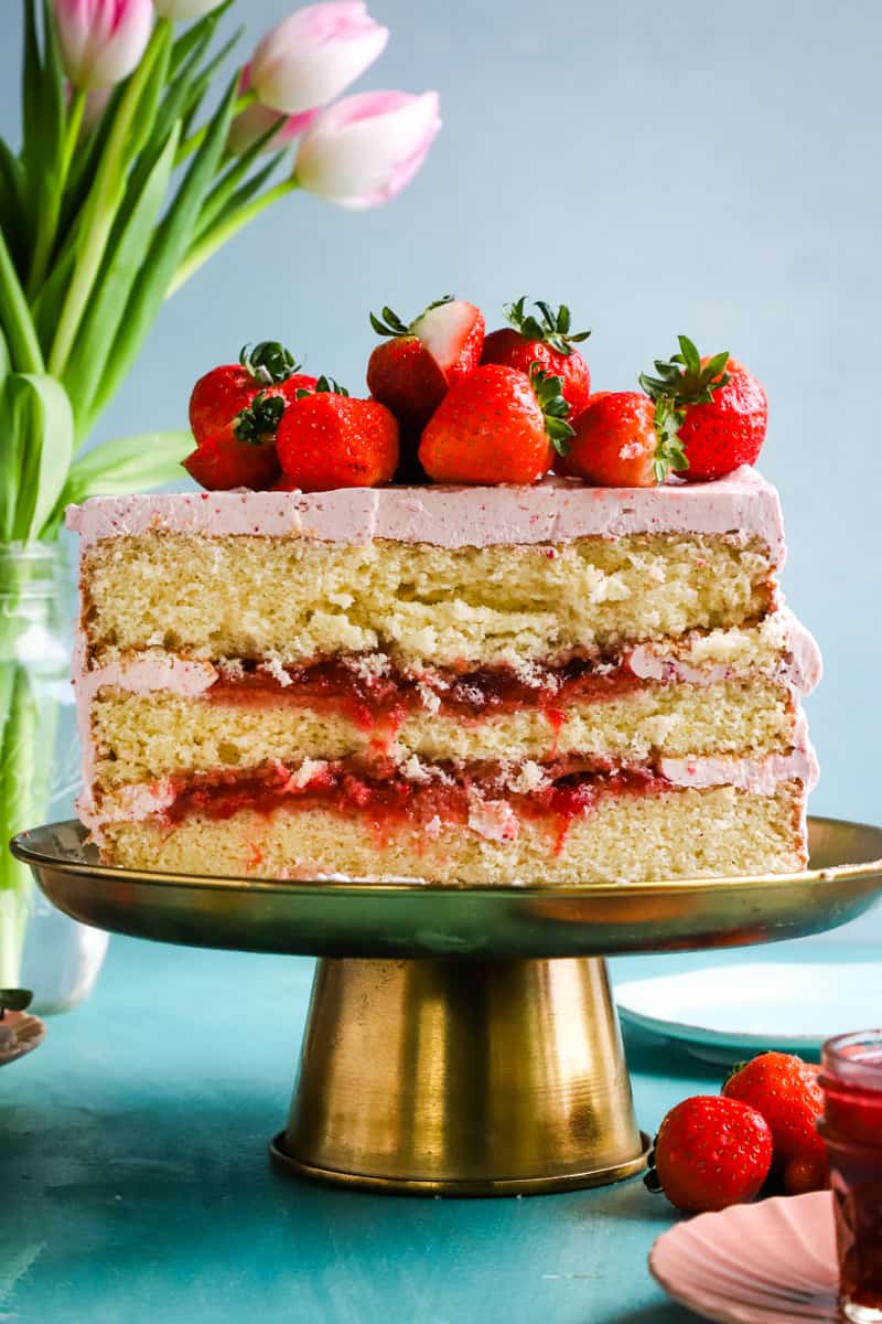 Cake cut in half showing the layers of cake and strawberry filling. 