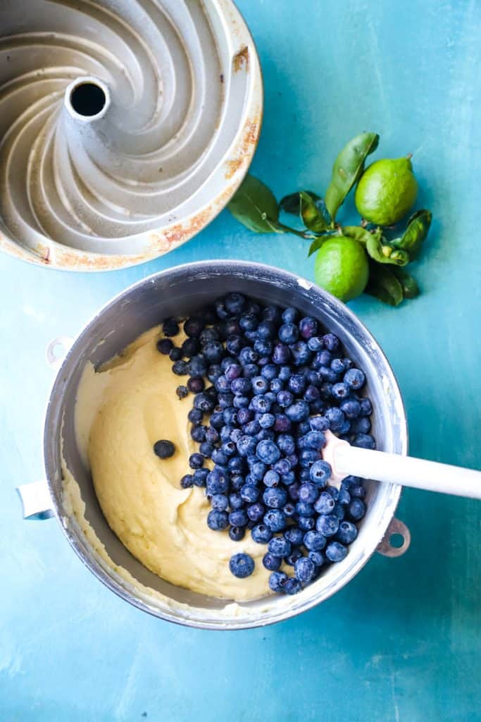 Stirring in the fresh blueberries to the batter in the large metal mixing bowl. 