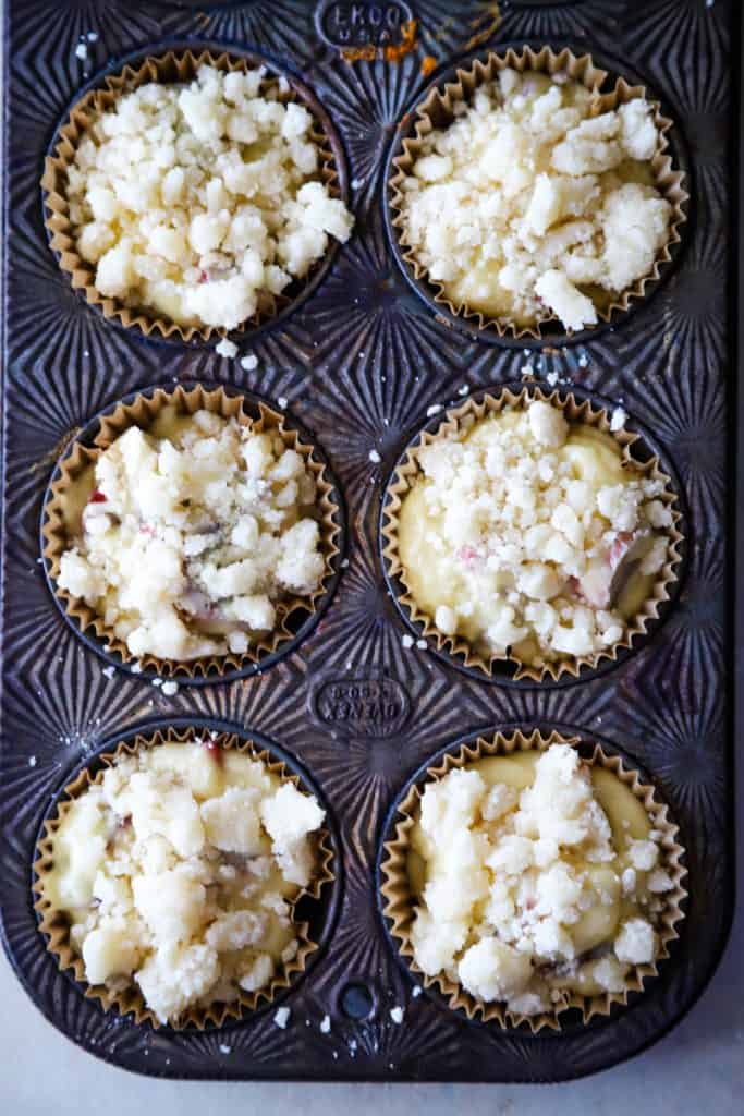 Adding the streusel topping to the tops of the unbaked muffins in tin. 