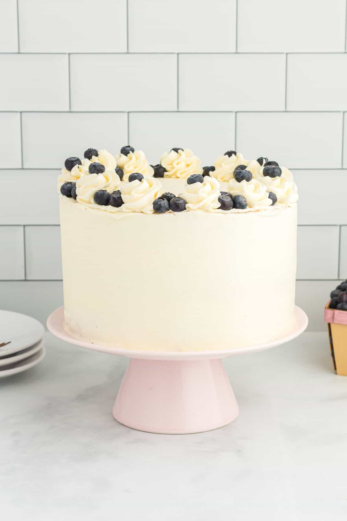 Whole cake with white frosting and fresh blueberries on top. 
