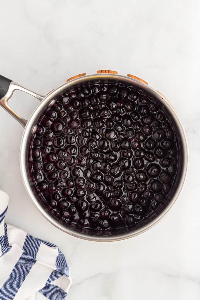 Overhead shot of the blueberries in a pan with blue and white dishtowel in corner. 
