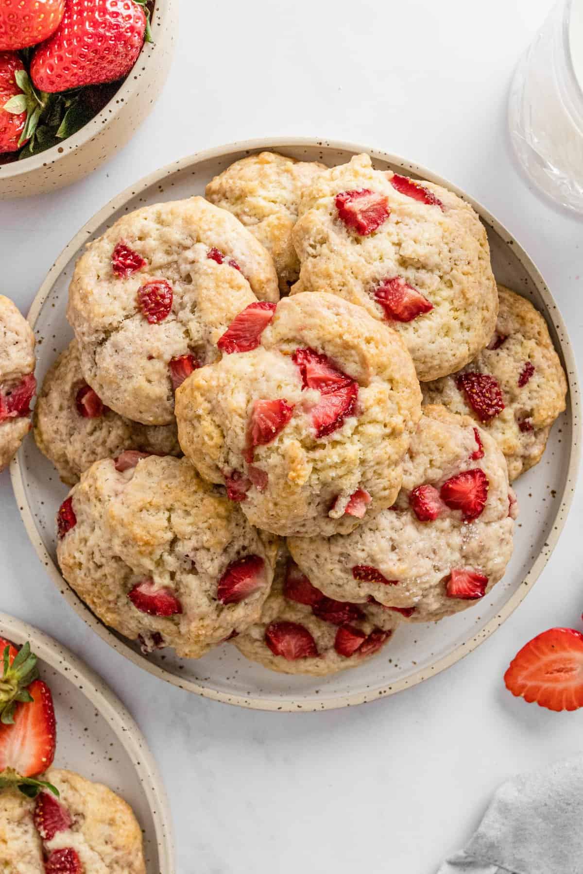 Cookies on round plate with bowl of strawberries in corner.
