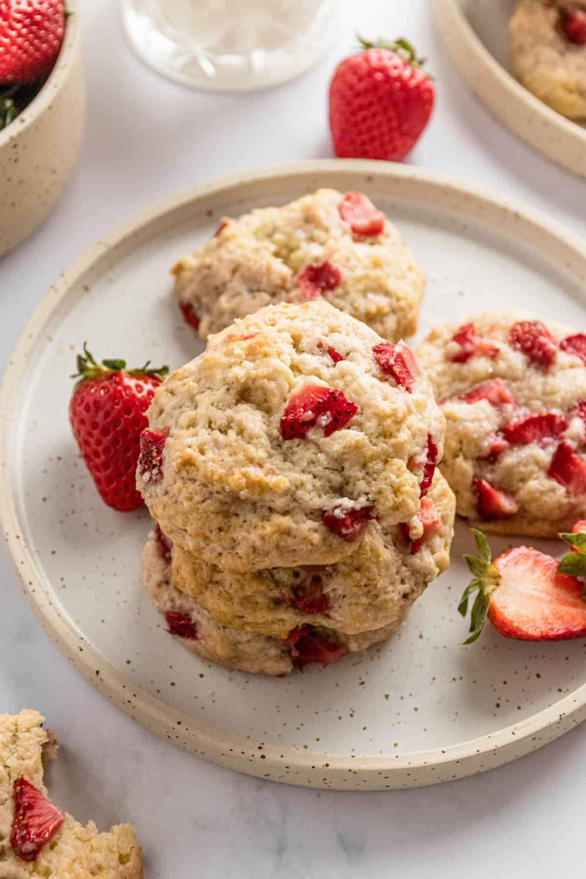 Angle view of the three stacked cookies on white plate with strawberries.