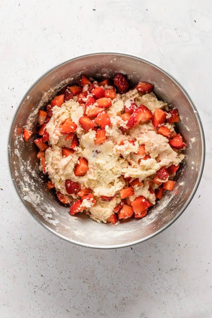 Large metal bowl with the shortcake cookie dough and fresh strawberries mixed in.