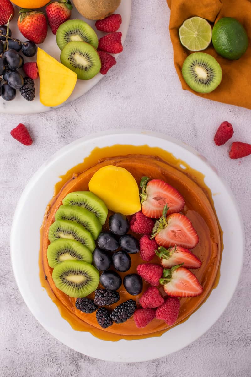 Overhead shot of the flan with the fruit on top on a white plate. 