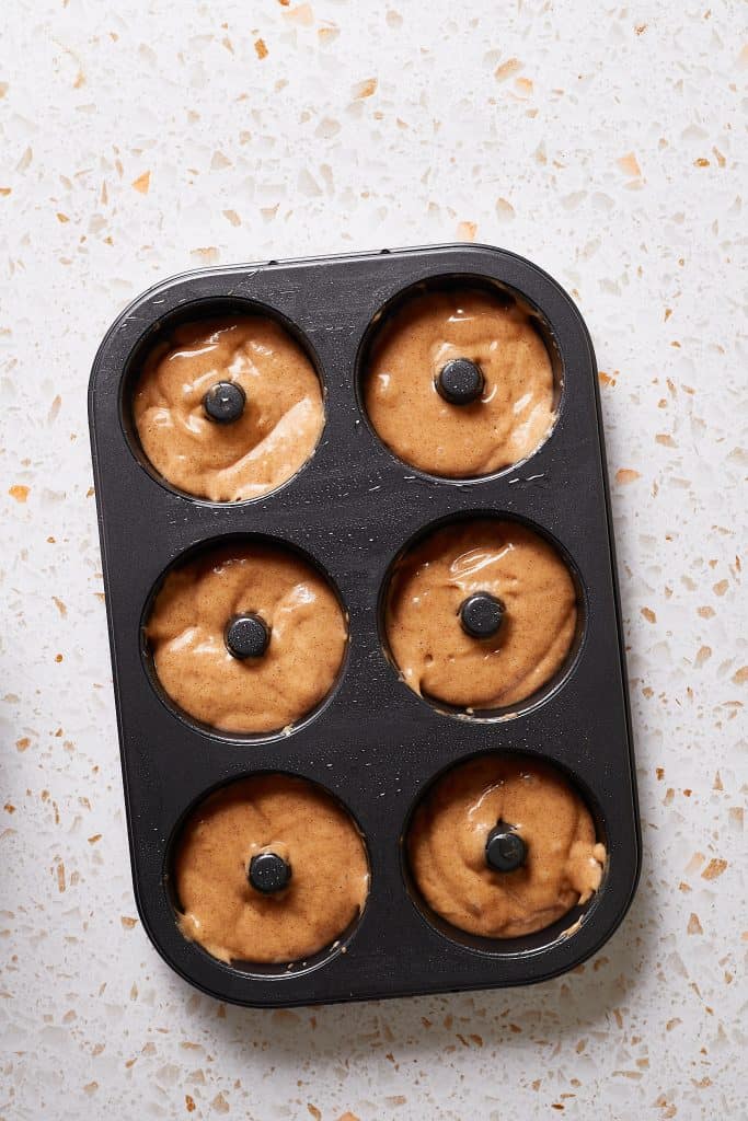 Piping the donut batter into the 6-cavity donut pan.