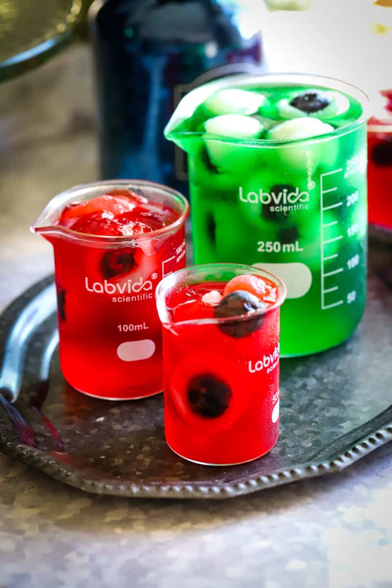 Different sized beakers with jello on a small metal plate.
