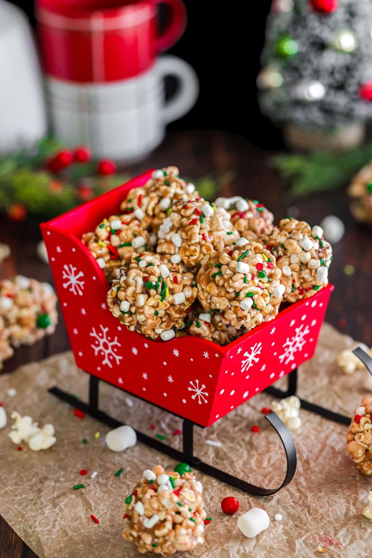 Little red sleigh filled with popcorn balls with sprinkles and marshmallows. 