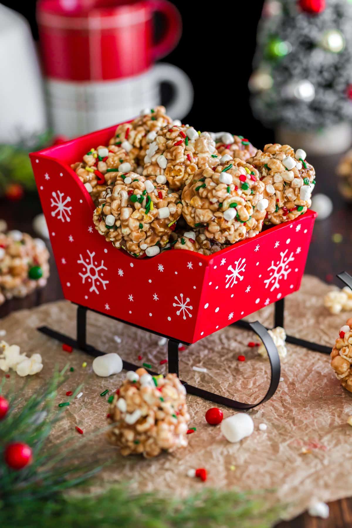 Cute Christmas popcorn balls in red sleigh on a piece of brown parchment paper. 