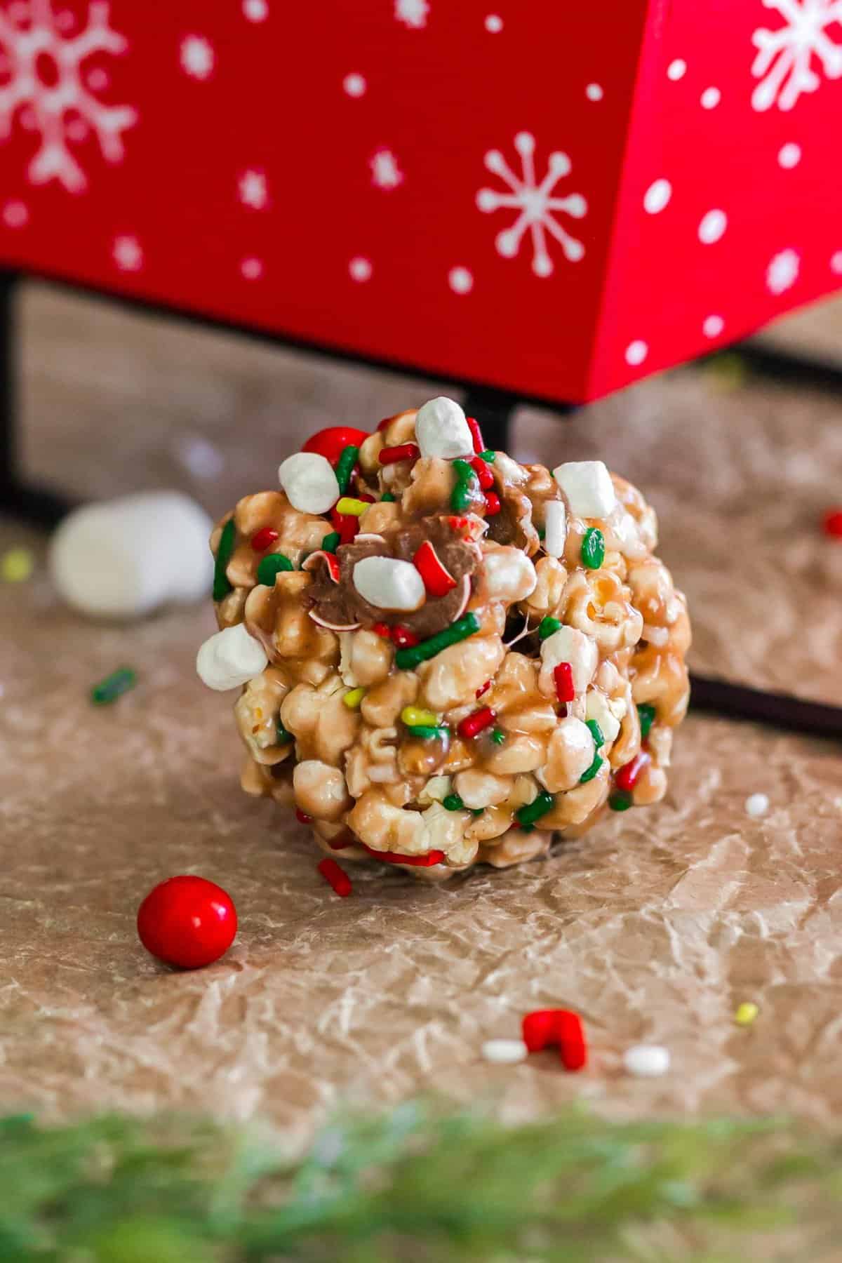 Up close shot of a popcorn ball with mini marshmallows and Christmas sprinkles. 