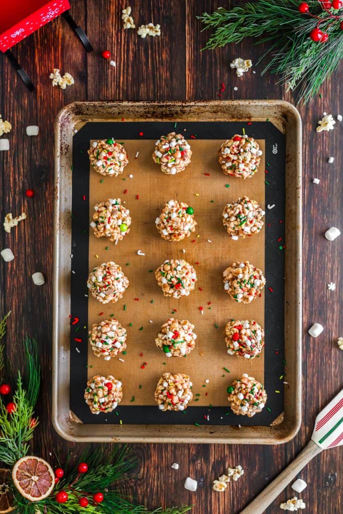 Rolled out popcorn balls with sprinkles on a silat lined cookie sheet. 