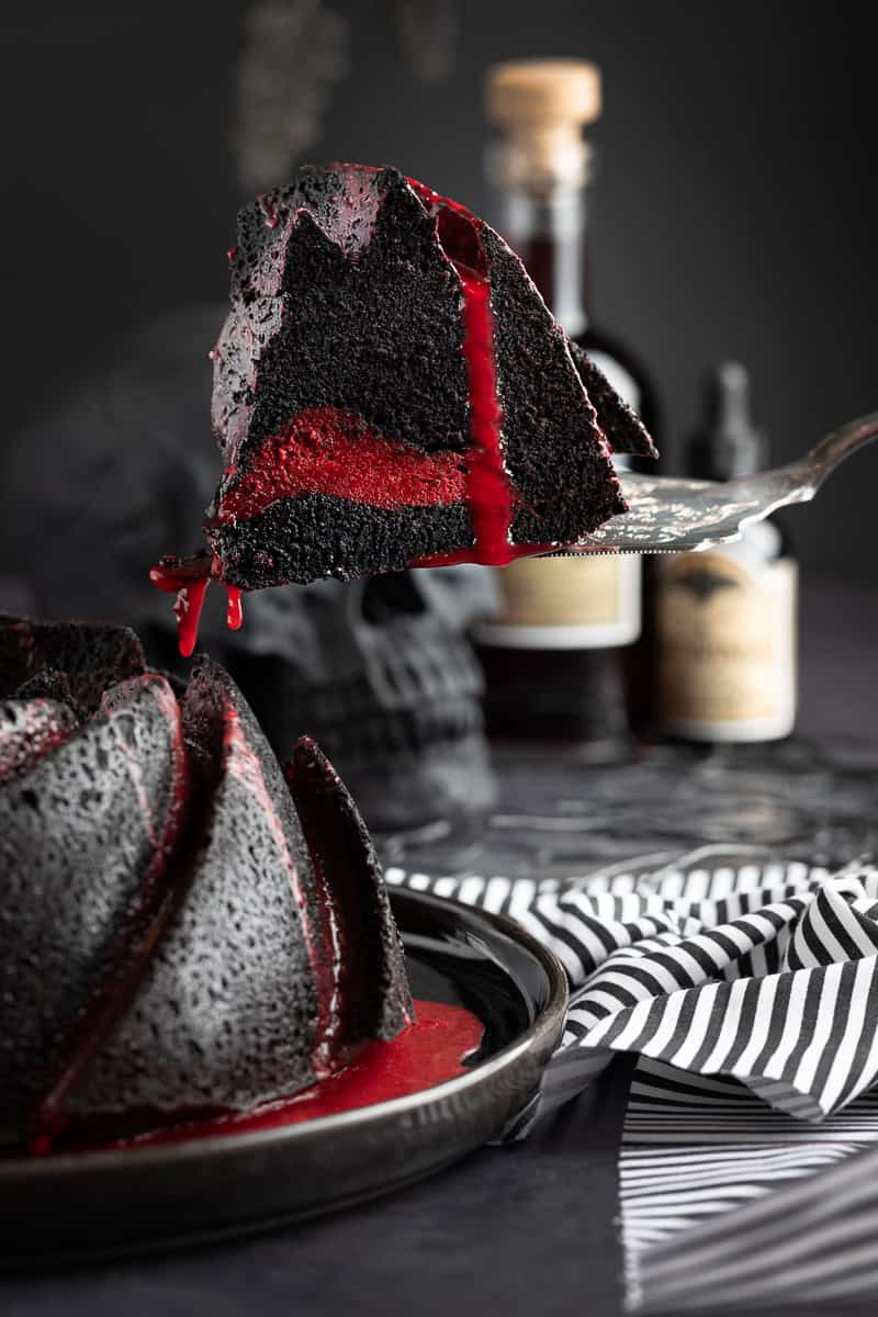 Cake slicer taking a slice of the bundt cake showing off the red cream cheese center. 