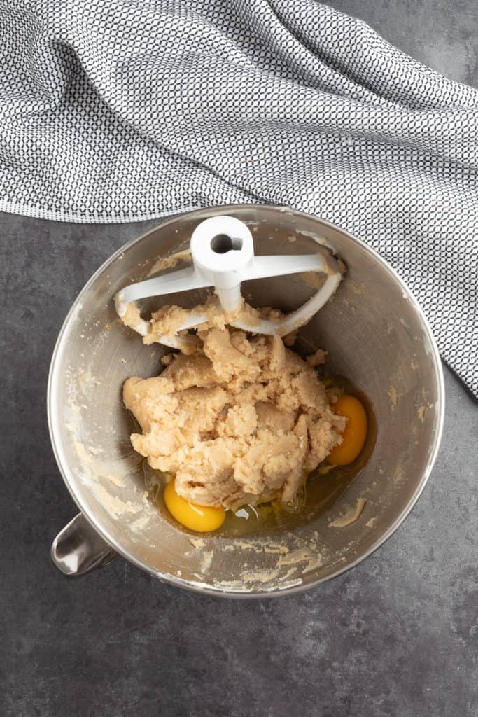 Adding the eggs to the creamed butter and sugar mixture in metal mixing bowl. 