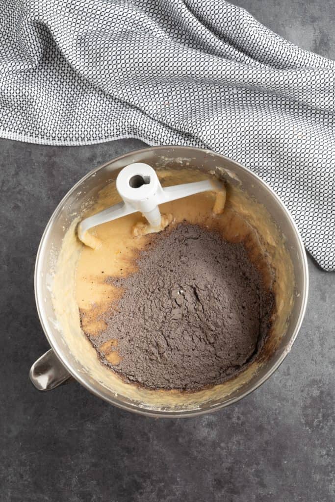 Gradually adding the dry flour mixture to the wet cake batter in a metal mixing bowl. 