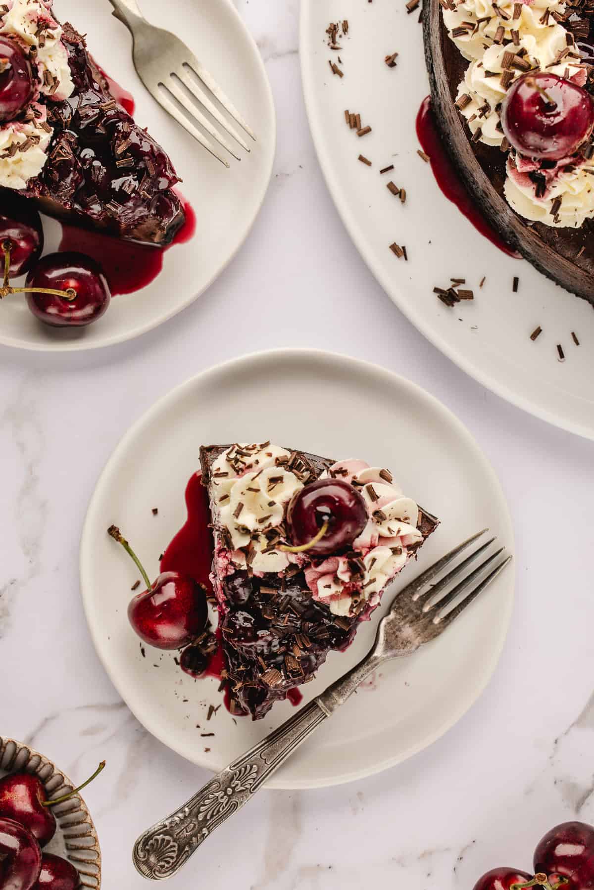 Overhead shot of slices of cheesecake on white plates with forks on white background. 