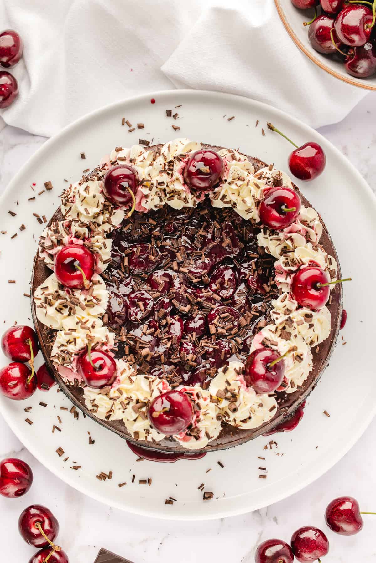 Overhead shot of the full cheesecake with garnishes on white plate. 