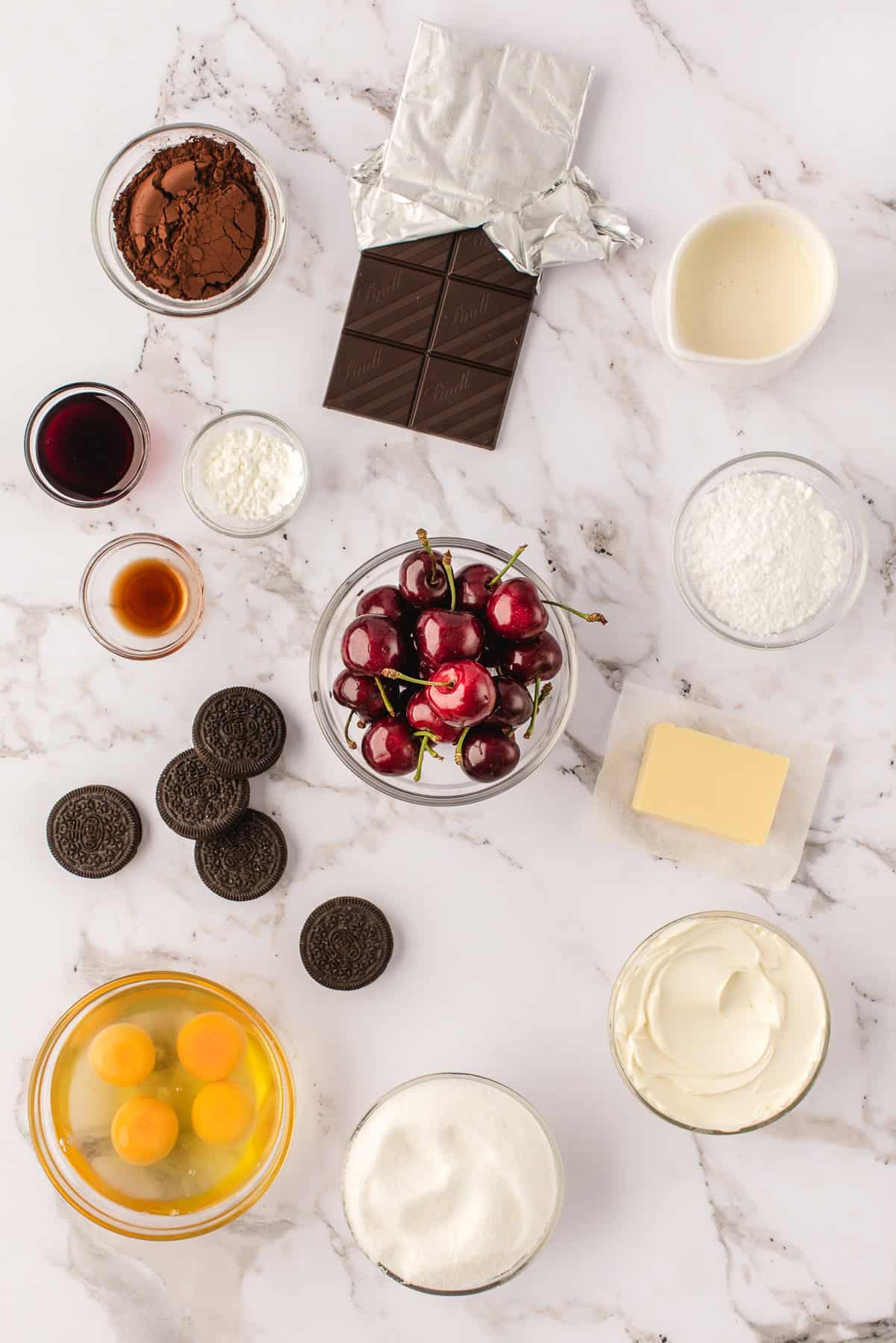 Overhead shot of the ingredients to make this cheesecake on white marble backdrop. 