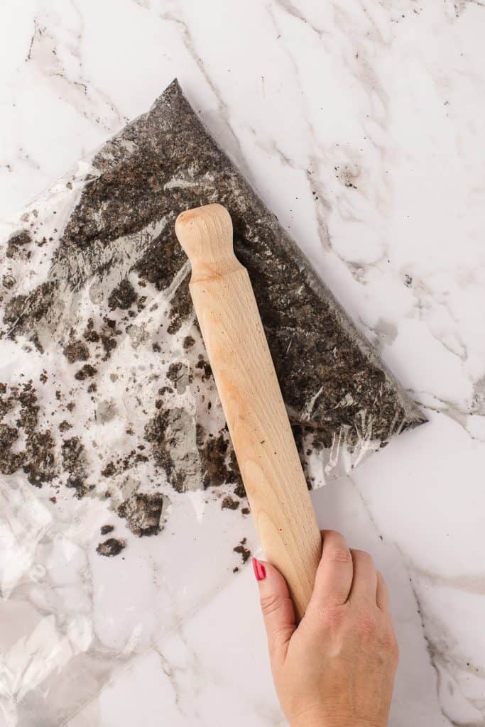 Crushing the Oreos in a bag with a wooden rolling pin.